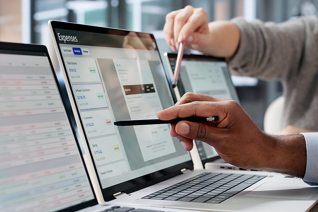 Finance employees reviewing expenses on a computer screen.